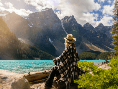 Woman looking across lake to mountains on horizon